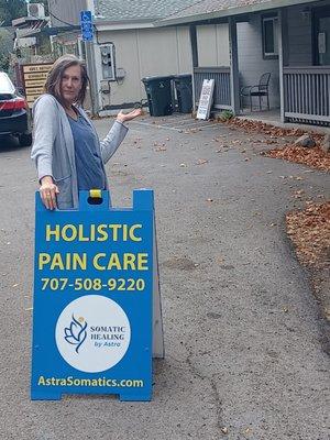 Holist Pain Care sandwich board with business owner.