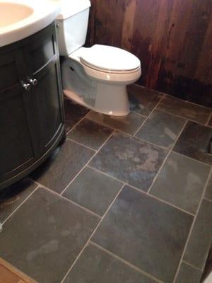 Reclaimed wood on the walls, new toilet and sink, and blue stone on the floor.