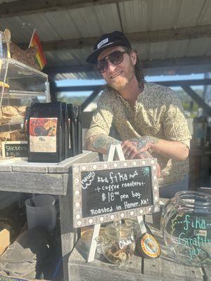 Tyler at the Homer Farmer's Market Booth next to bags of Fika coffee!