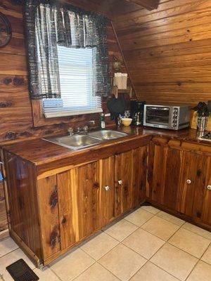 A-frame Cabin 6 kitchen with cedar cabinets, sink and coffee maker.