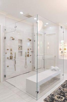 Custom shower with dual showerheads, hidden floor drain along the shower wall and a shower bench