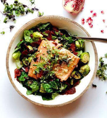 Delicious Fall salmon salad with roasted Brussels sprouts, turkey bacon and pomegranate seeds over baby kale!