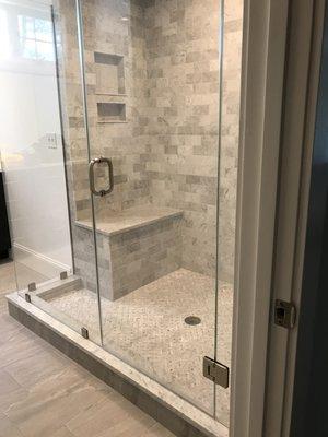 frameless shower with return panel, side panel, and door with chrome clips, handle, and hinges.