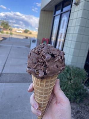 Single scoop of chocolate brownie ice cream on a waffle cone