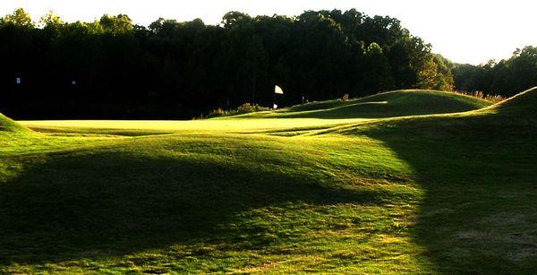 Sun setting over the green on 18, which is a par 4 and measures 437 yards from the tips. Water comes into play at the tee boxes and greens.