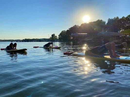 SUP yoga at Lake Milton under the glow of the sun setting across the water.