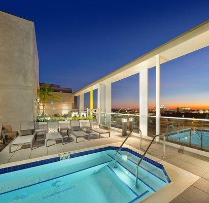 A glamorous rooftop deck with pool, lounge area with firepit, and BBQ.