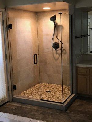 TILE SHOWER WITH STONE FLOOR AND GLASS ENCLOSURE