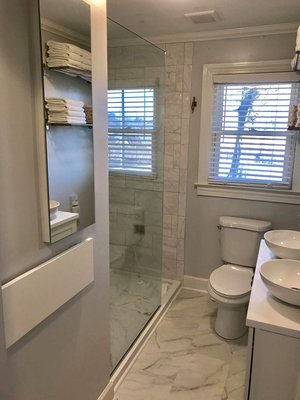 Bathroom remodel including custom tiling, flooring, shelving, glass shower door, new toilet, new sinks and cabinetry, medicine cabinet