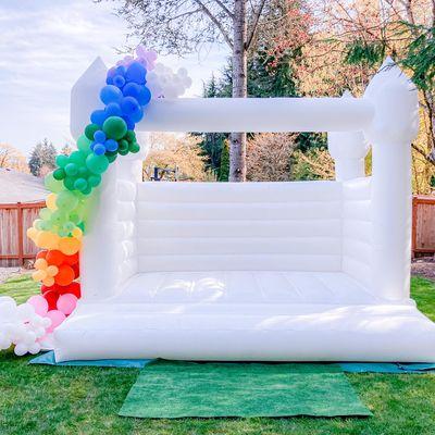 White bounce house with balloon garland