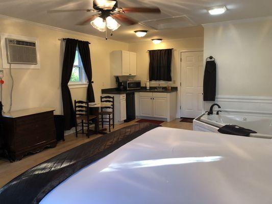 view from the front door into cottage showing the king bed, sitting area with kitchenette and jacuzzi