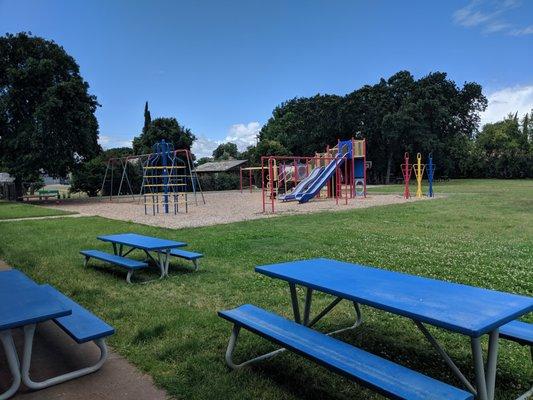 Playground equipped with slides, swings, and monkey bars. A large field for soccer, kickball, tetherball, etc. Benches for lunch time.