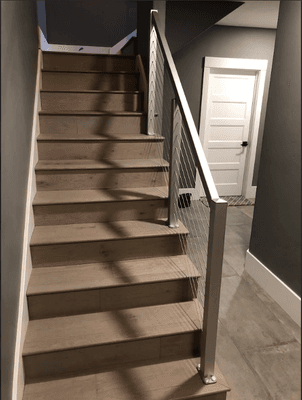 Gray Aluminum Top Rail with Stainless Steel Cable Infill installed on indoor stairs. Perfect for all indoor and outdoor railing purposes!