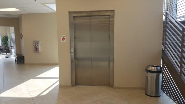 First floor elevator with stairs behind.