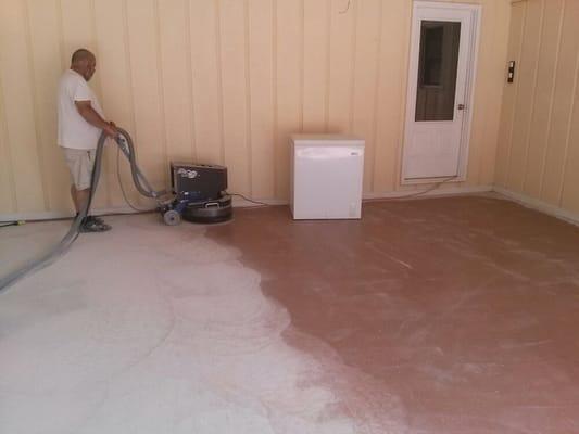 Garage floor with an inferior paint coating is being ground down and prepared for an epoxy coating with chips.