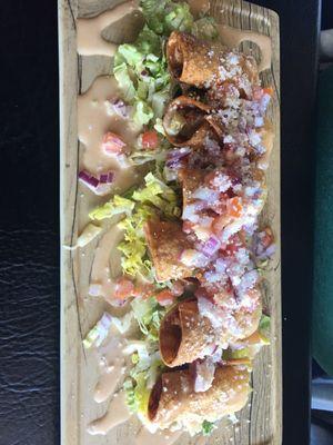 Flautas El Pirate a mix of rolled and deep fried Shrimp, cheese, poblano sauce, guacamole, lettuce red onion and cortina.