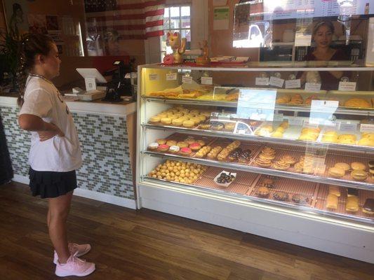 Counter with savory items top shelf, donuts middle two and eclairs, etc on bottom.