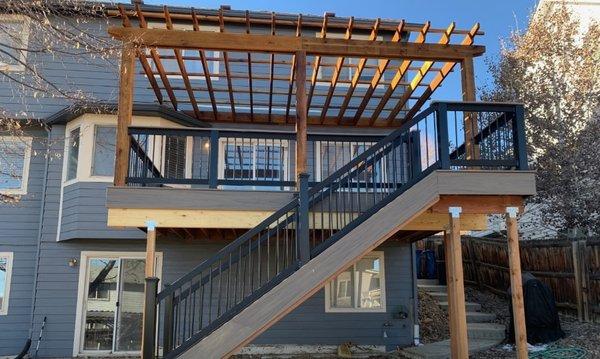 Wood pergola to provide shade over composite deck with iron railing.