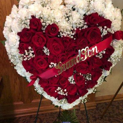 This heart shaped easel with roses carnations and baby's breath..