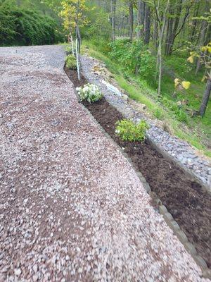 New light fixtures with new flower bed along the driveway with fresh brown mulch