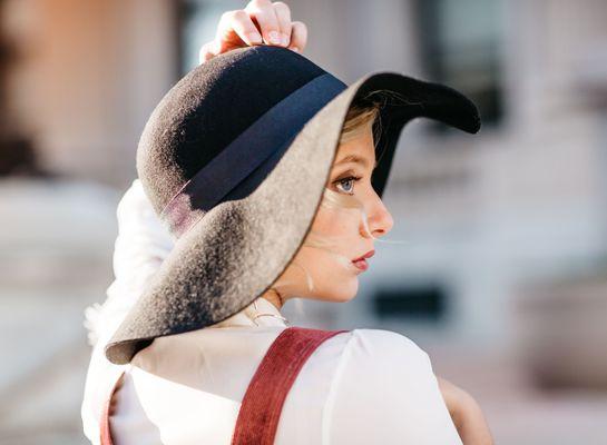 An attractive woman wearing a floppy hat is posing for a senior portrait in downtown in Indianapolis IN