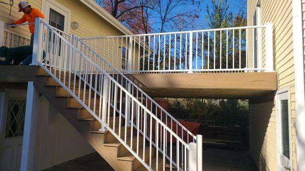 Modern deck renovation in progress, showcasing sleek white railings and sturdy composite stairs