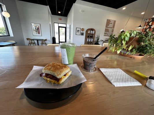 Biscuit sandwich (bacon egg and cheese), iced matcha, strawberry chia seed pudding, inside dining area