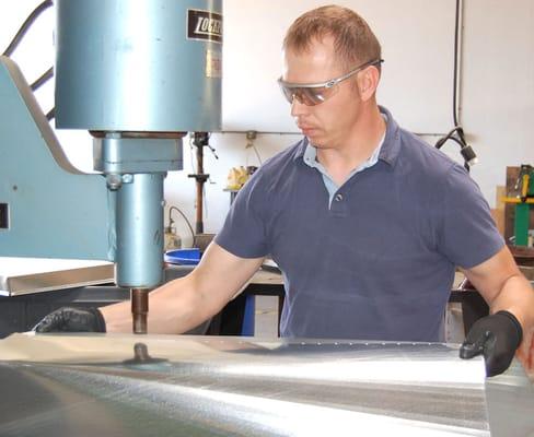 A COAC Sheetmetal Craftsman rivets a section of custom ductwork for new HVAC installation