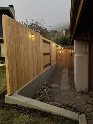 Cedar fence with steel posts on new concrete wall with solar lighting