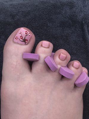 Pedicure with pink nails and cherry blossom design for luck,