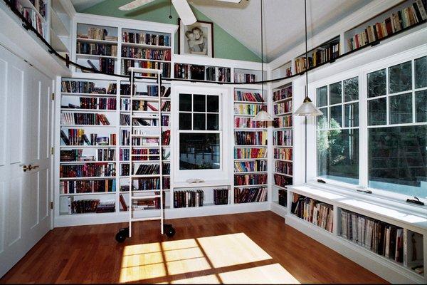 Home library covering four walls with a library ladder running all around.