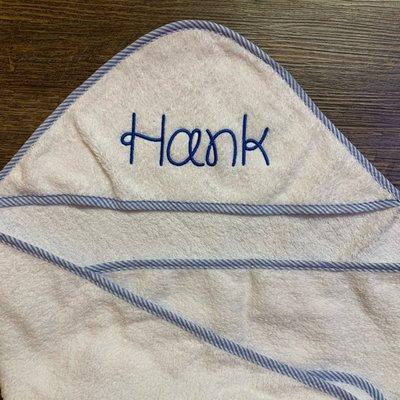 Royal blue thread embroidered on a baby hooded towel in premium Dear Doily font.