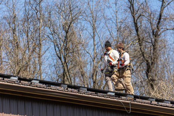 Exact Solar installers working safely on the roof, planning a new installation for a barn.