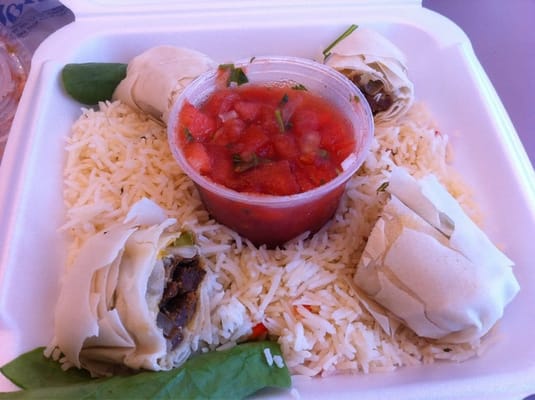 Steak fajita egg rolls on rice with spinach leaves