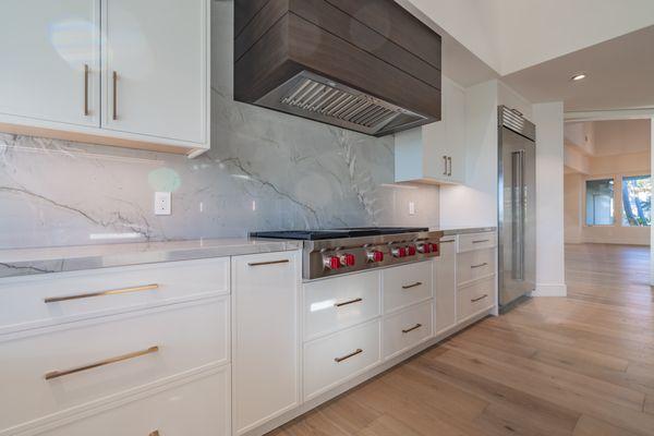 New cabinets, hood, appliances, natural stone quartzite backsplash, and wood  flooring.