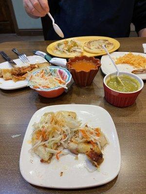 Half eaten bean and cheese pupusas in front   Then slaw, sauces - Spicey but great touch!