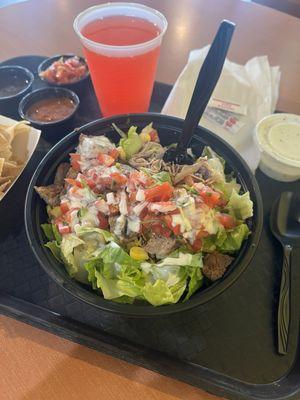 Salad bowl with rice, pinto beans, grilled chicken, pork carnitas, corn, pico, and lettuce.