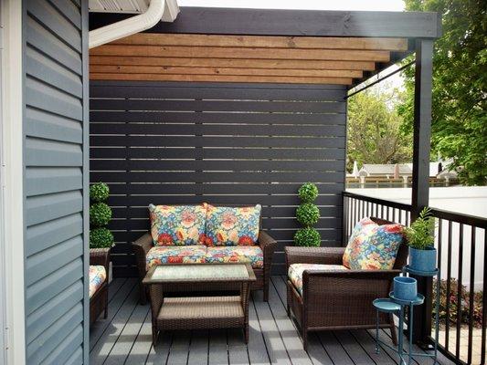 Small rear deck with privacy wall and pergola.