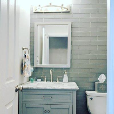 Blue-gray powder room with wall-to-wall glass tile, marble vanity