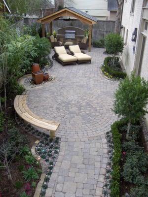 Custom designed walkway to circular paver patio with bench, water feature, gable roof addition, and an Outdoor Kitchen.