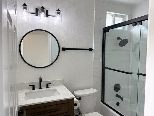 Stunning hall bath remodel with sleek matte black fixtures and a premium quartz vanity.