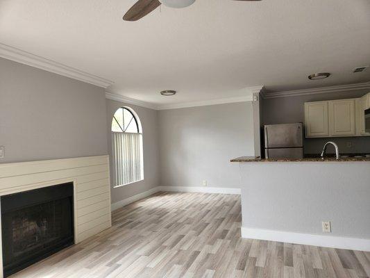 Modernized fireplace in living room at matching color on the kitchen cabinets also recently painted, crown molding.