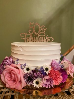 A vanilla cake with lemon mousse, simply decorated with fresh flowers for a 50th birthday.