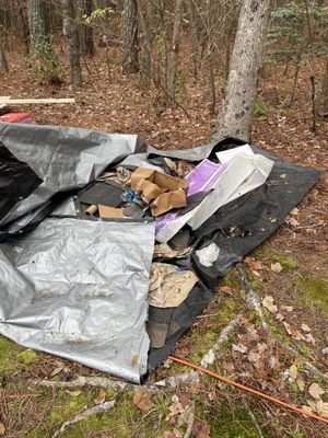 Empty boxes, loose roofing, nails, and even drink bottles, all covered by a tarp.