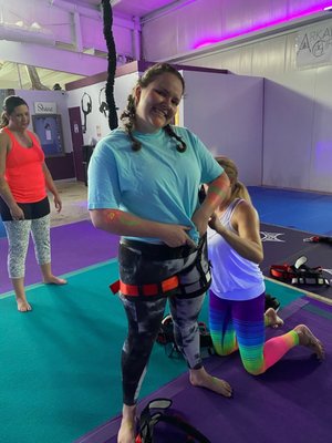 Me getting my harness put on by Christy for our Glow Bungee Drop-In class!