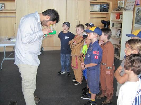 Michael shows the kids how to look through the magnifying tool to see the small pond critters that they captured.