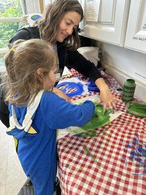 Teacher Tacha helping my daughter paint her Earth Day Shirt.