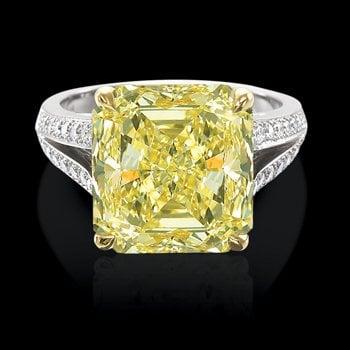 Radiant cut yellow diamond ring set in platinum with white diamonds decorating the shank.