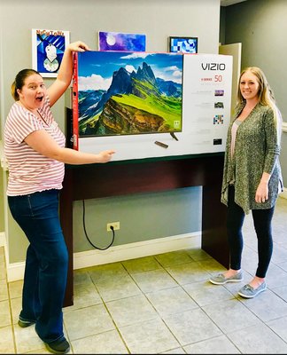 Pharmacy Technician Leslie Hayes (L) and Pharmacist Bailey Huskins (R) holding up the TV that we are giving away for our Grand Opening.