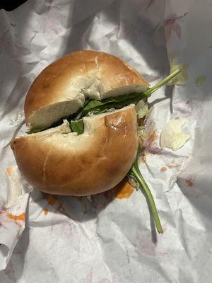 Roast beef on a plain bagel with spinach, lettuce, onions, sweet peppers and buffalo sauce